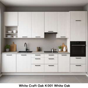 Moderne Einbauküche mit matten Fronten in White Craft Oak K001 Dekor, schwarzen Griffen, integriertem Backofen und minimalistischer Ausstattung vor neutraler grauer Wand.
